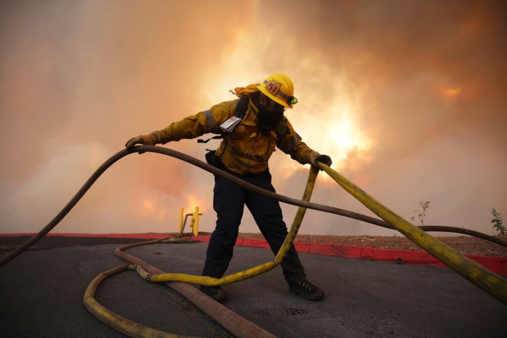 A firefighter sets out fire hoses to fight the Hughes Fire on Wednesday.