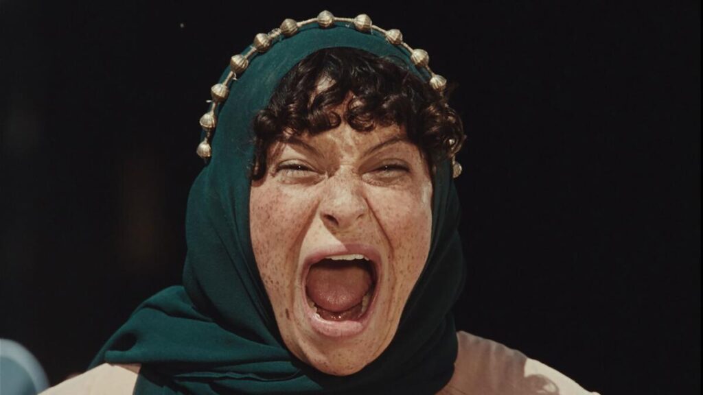 A woman in a headscarf shouts.