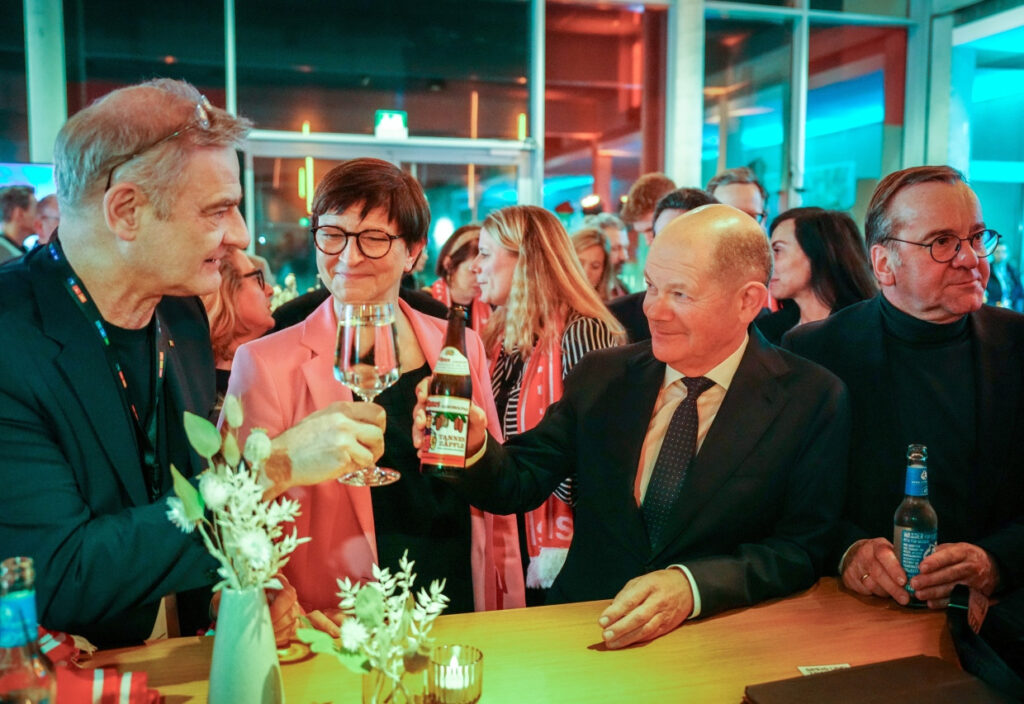 Nach dem Quadrell: Bundeskanzler Olaf Scholz stößt mit dem Schauspieler Heinrich Schafmeister (links) an.