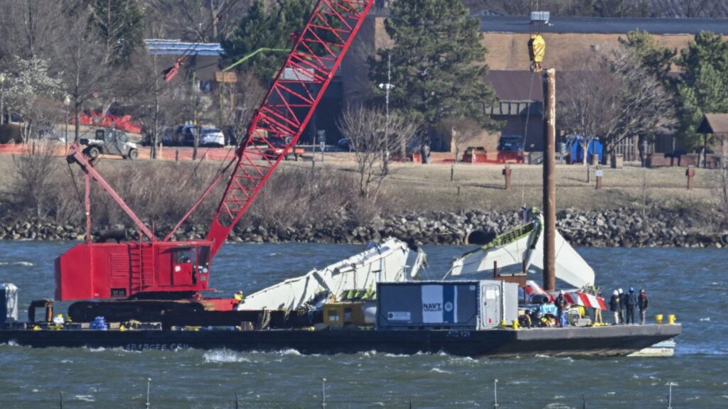 US Navy recovery teams lift the back wing section of an American Airliners plane from the Potomac in Arlington, Virginia on February 4, 2025. Operations to salvage the wreckage from a deadly collision between a US Army helicopter and a passenger jet continued as rescuers said 55 victims had so far been identified. Dozens of victims have been pulled from the icy Potomac River, and rescuers voiced confidence that those remaining would be retrieved in the massive operation to recover the plane that collided in midair with a Black Hawk military helicopter. (Photo by ROBERTO SCHMIDT / AFP) (Photo by ROBERTO SCHMIDT/AFP via Getty Images)