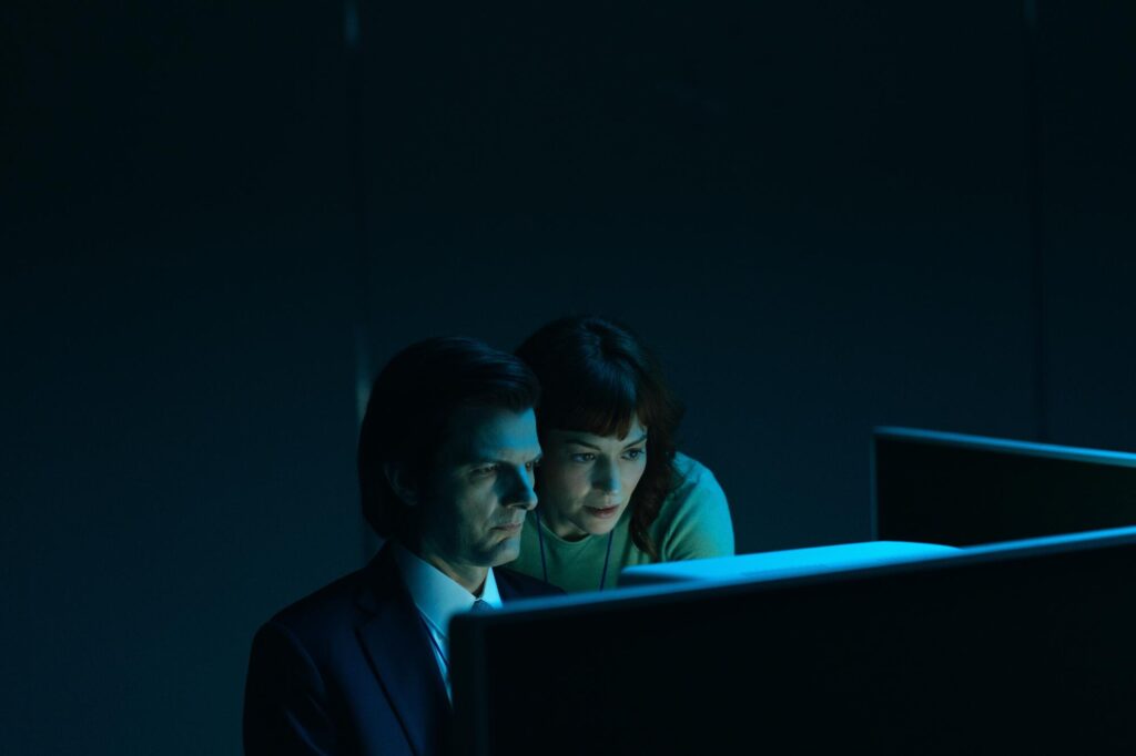 A man and a woman, their faces nearly touching, looking closely at a computer screen.