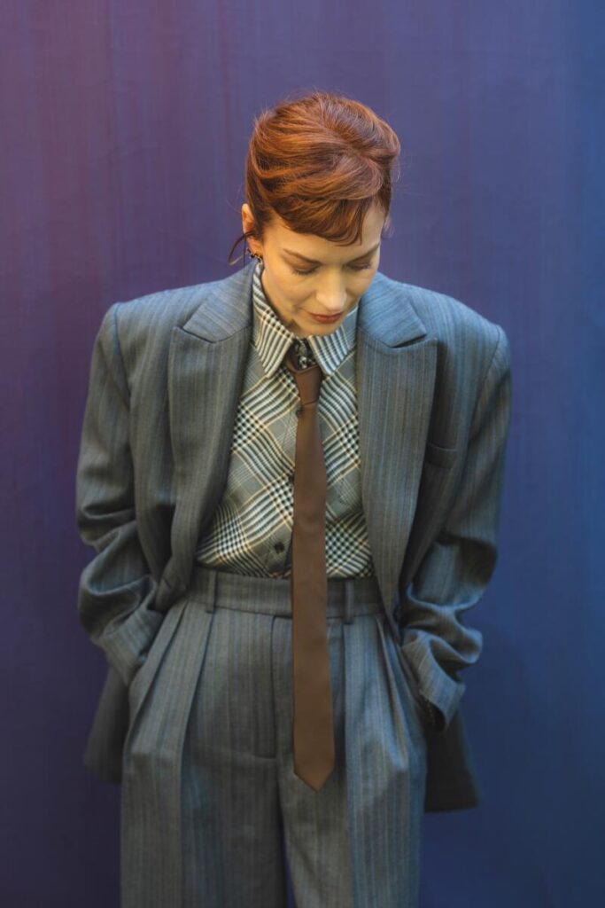 A woman in a grey suit looking downward.