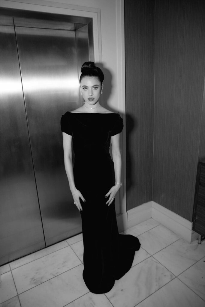 a figure in a black evening gown standing near an elevator