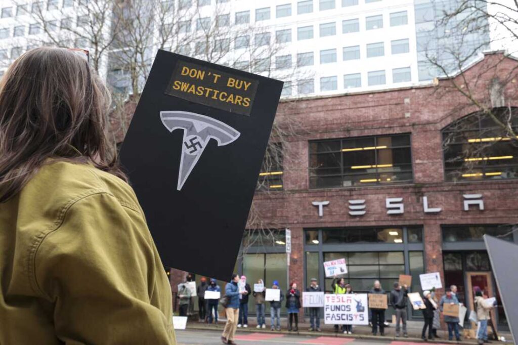 People participate in a "TeslaTakedown" protest against Elon Musk outside of a Tesla showroom in Seattle, Washington, on February 15. Musk's job-cutting efforts at the "Department of Government Efficiency," along with controversial remarks and a straight-armed gesture, have prompted a widespread backlash against him and his companies. Tesla's brand has been growing more politicized for several years now.